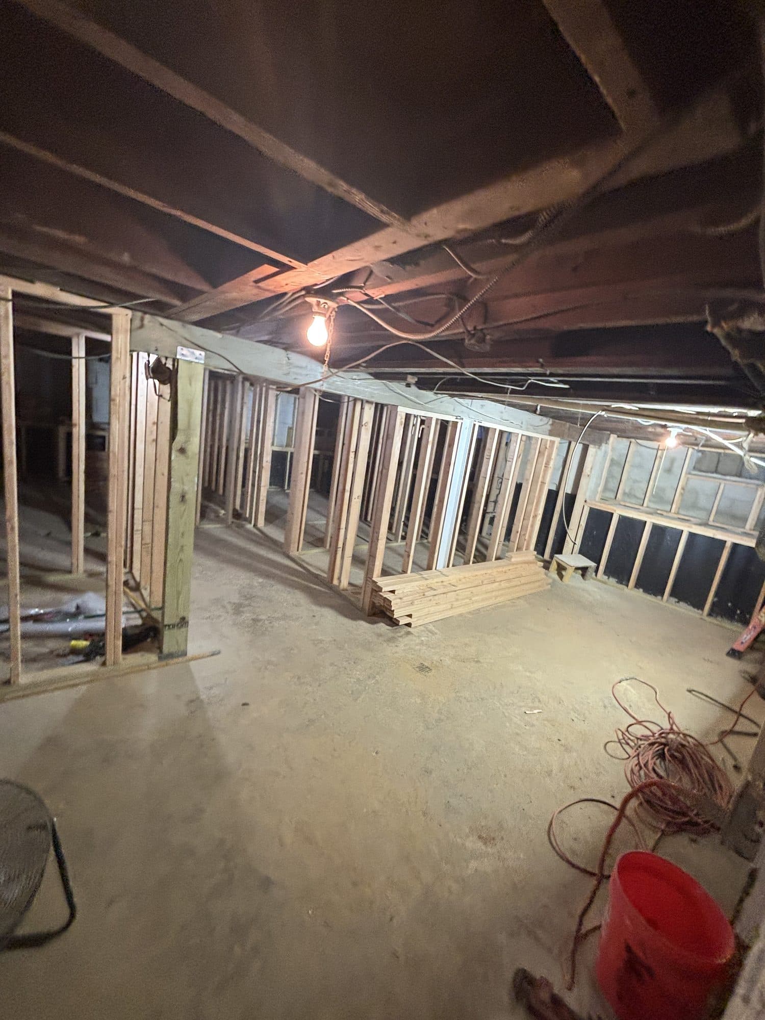 Wood stud partition walls line a long basement being framed for finishing under exposed joists. Home addition project by Potts Brothers Construction, Arlington & Northern Virginia