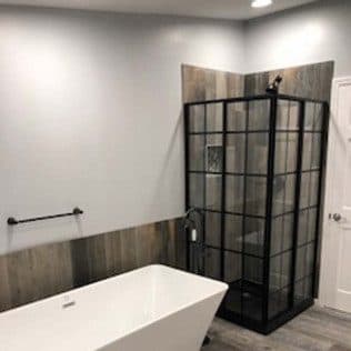 Bathroom with freestanding tub and black-framed glass shower. Home addition project by Potts Brothers Construction, Arlington & Northern Virginia