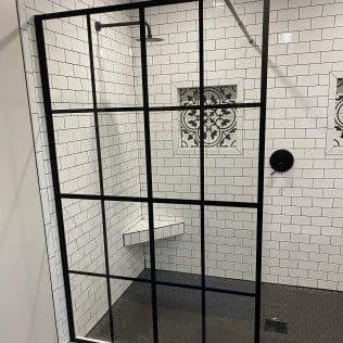 Black-framed glass shower with white subway tile. Home addition project by Potts Brothers Construction, Arlington & Northern Virginia
