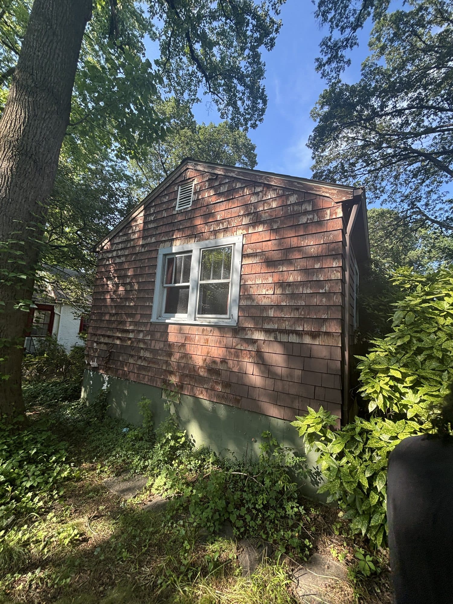 Cedar shingled cottage gable end among trees. Home addition project by Potts Brothers Construction, Arlington & Northern Virginia
