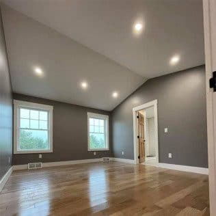 A finished bedroom with a vaulted ceiling, recessed lights, oak flooring, and gray walls. Home addition project by Potts Brothers Construction, Arlington & Northern Virginia
