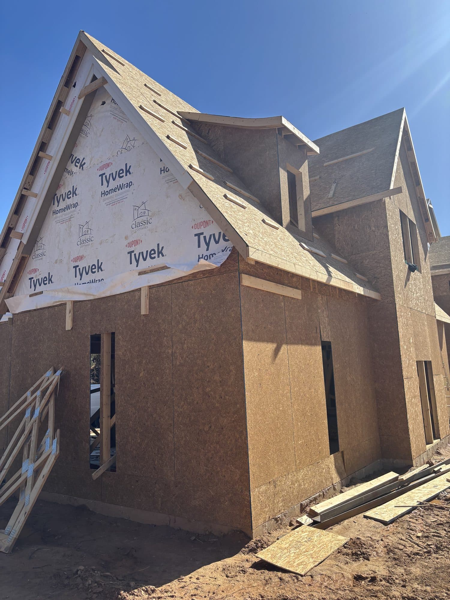 A two-story addition framed with OSB sheathing and Tyvek housewrap under a clear sky. Home addition project by Potts Brothers Construction, Arlington & Northern Virginia