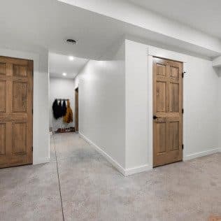 Finished basement hallway with wood doors and concrete floor. Home addition project by Potts Brothers Construction, Arlington & Northern Virginia