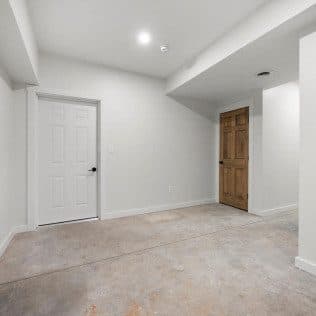 A freshly finished basement room with two new doors, smooth walls, and recessed lighting. Home addition project by Potts Brothers Construction, Arlington & Northern Virginia