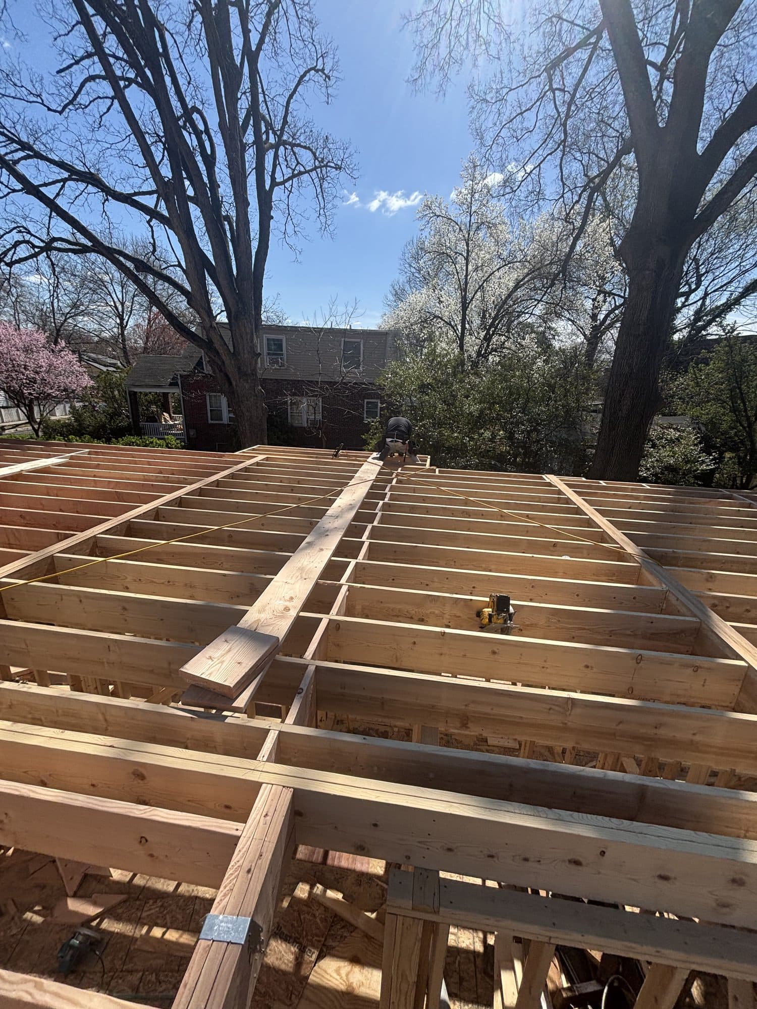 Floor joist framing of large addition under blue. Home addition project by Potts Brothers Construction, Arlington & Northern Virginia