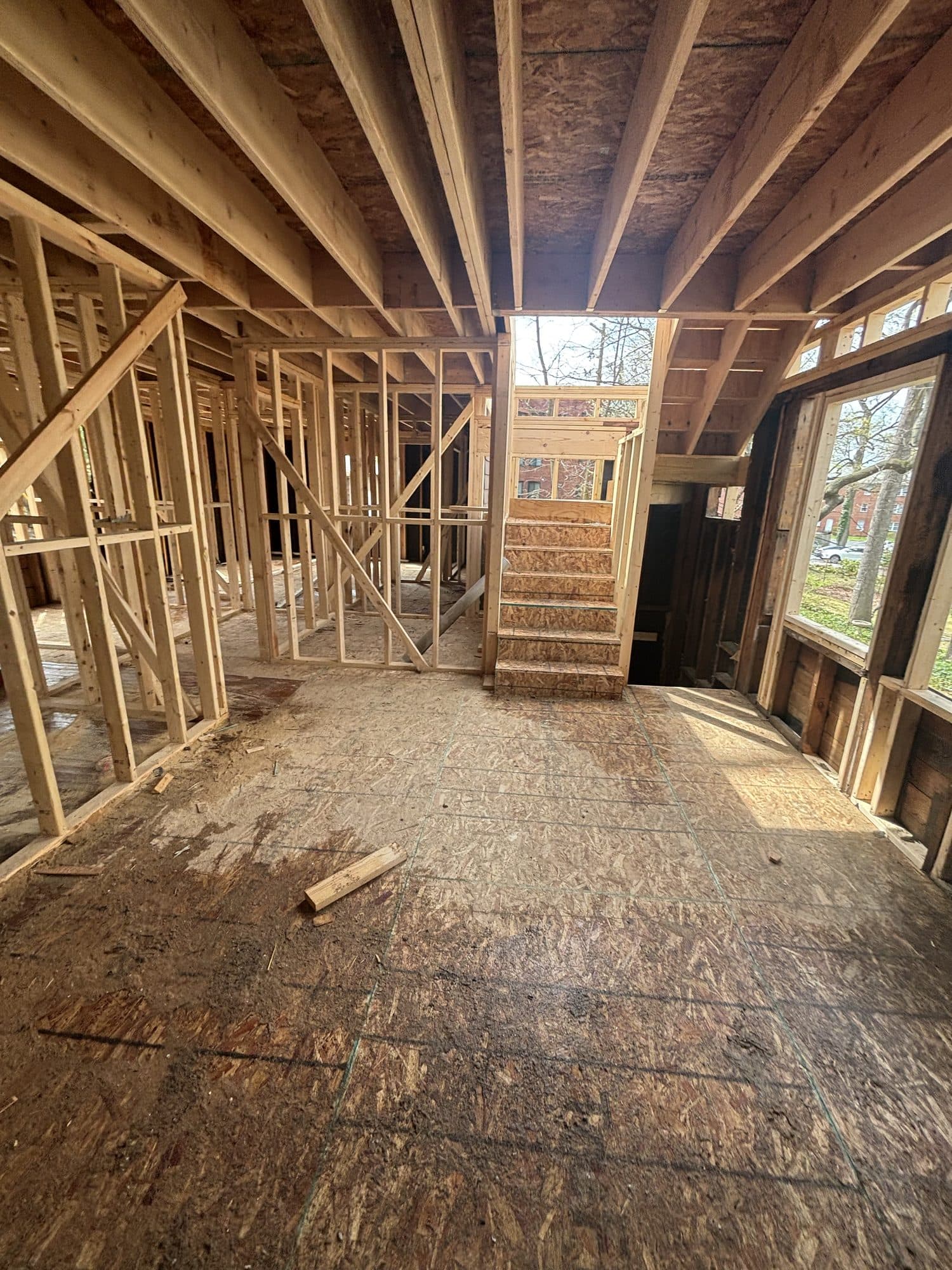 Stud-wall framing of an addition wraps a new staircase opening with a window wall to one side. Home addition project by Potts Brothers Construction, Arlington & Northern Virginia