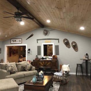 A family room with a wood-plank vaulted ceiling, exposed beam, ceiling fan, and gray walls. Home addition project by Potts Brothers Construction, Arlington & Northern Virginia