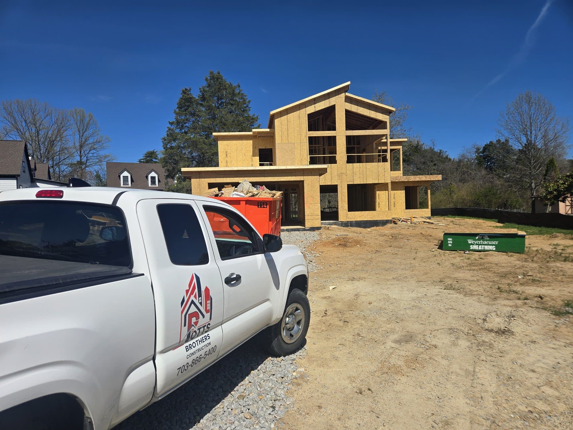 A Potts Brothers truck parked in front of a two-story home framed and sheathed during construction. Home addition project by Potts Brothers Construction, Arlington & Northern Virginia