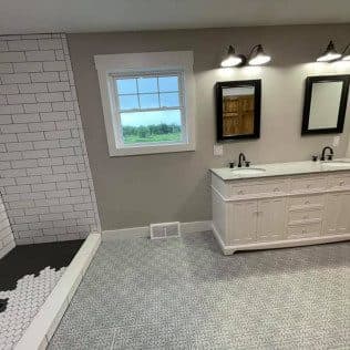 A remodeled bathroom with a white double vanity, a subway-tiled walk-in shower, and a mosaic tile floor. Home addition project by Potts Brothers Construction, Arlington & Northern Virginia