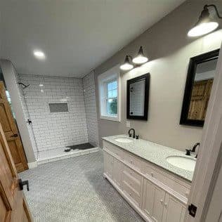 A remodeled bathroom with a subway-tiled walk-in shower, white double vanity, and barn-light sconces. Home addition project by Potts Brothers Construction, Arlington & Northern Virginia