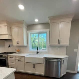 A renovated kitchen with white cabinetry, a farmhouse apron sink, subway tile backsplash, and stainless appliances. Home addition project by Potts Brothers Construction, Arlington & Northern Virginia