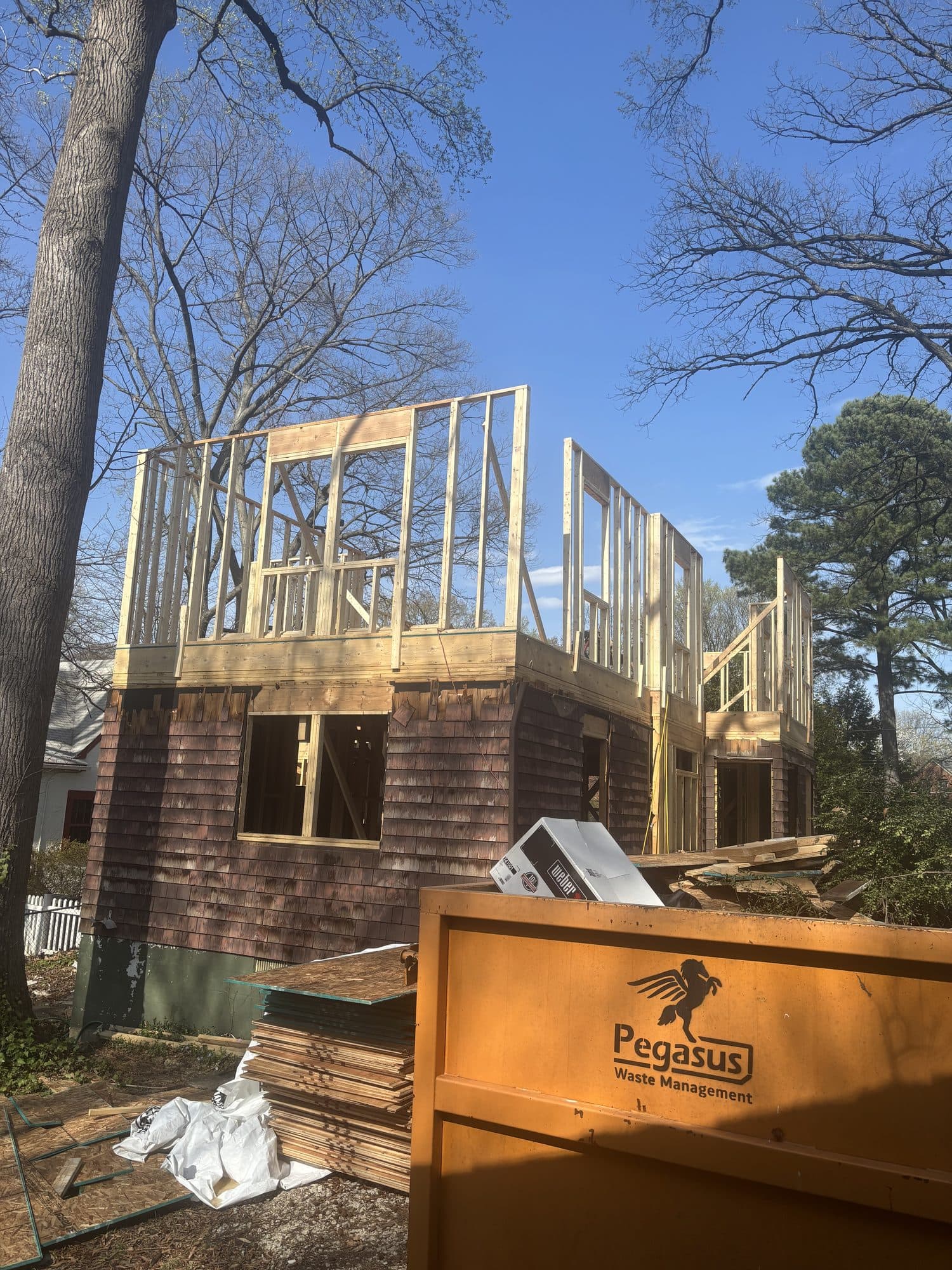 A new second-story addition is framed above the existing cedar-shake-sided first floor. Home addition project by Potts Brothers Construction, Arlington & Northern Virginia