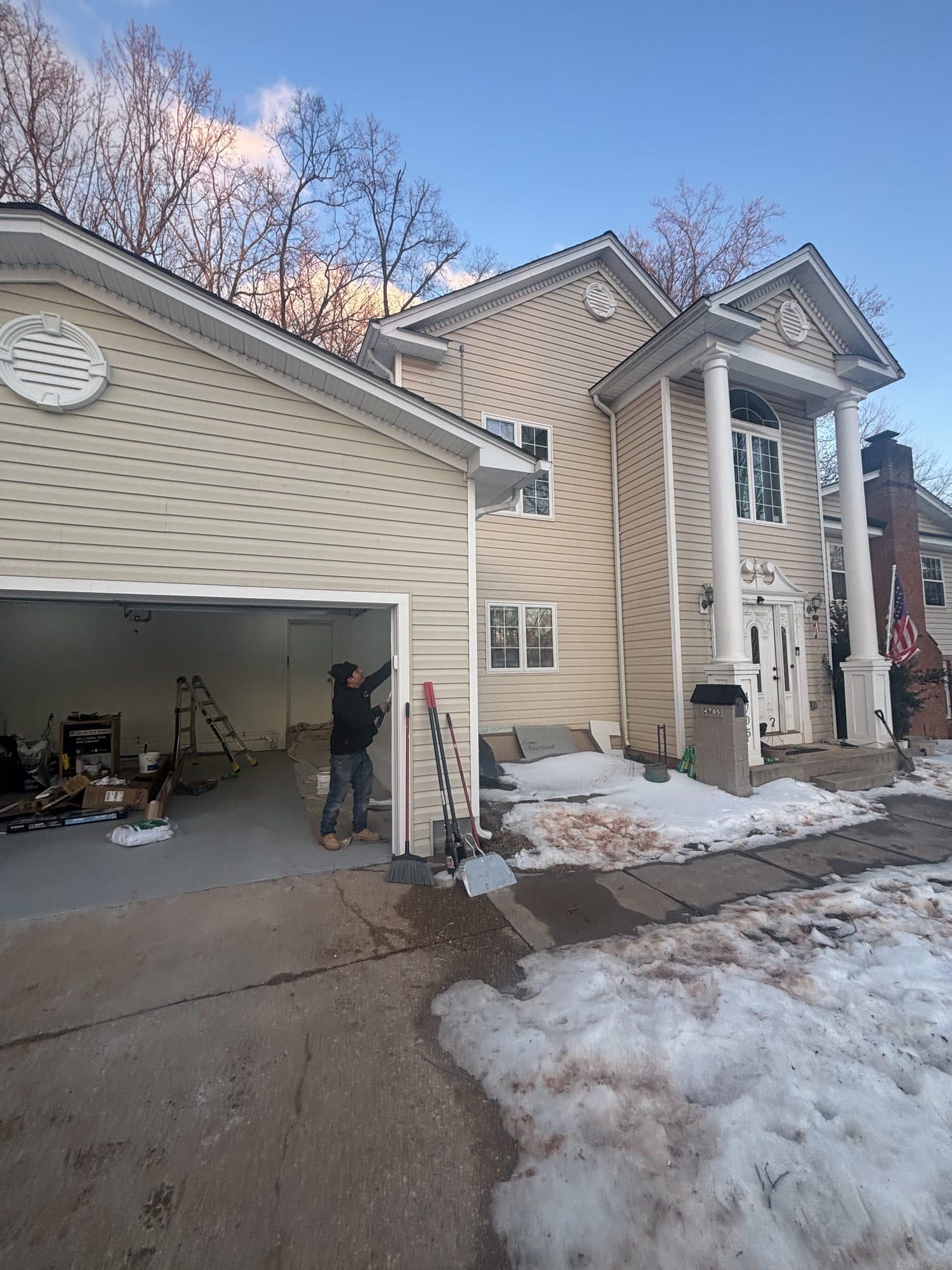 A finished tan two-story home with a columned portico entry and attached two-car garage at dusk. Home addition project by Potts Brothers Construction, Arlington & Northern Virginia