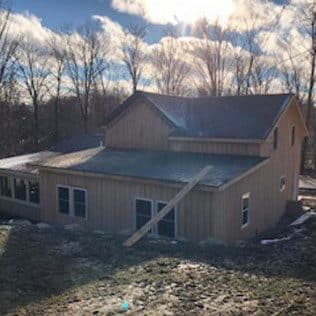 A completed two-story addition clad in vertical cedar siding with a low-pitch gable against bare winter trees. Home addition project by Potts Brothers Construction, Arlington & Northern Virginia