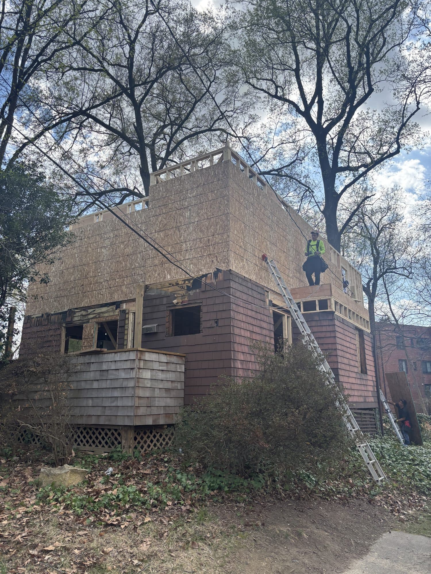 Worker atop cedar shake home with new second sto. Home addition project by Potts Brothers Construction, Arlington & Northern Virginia