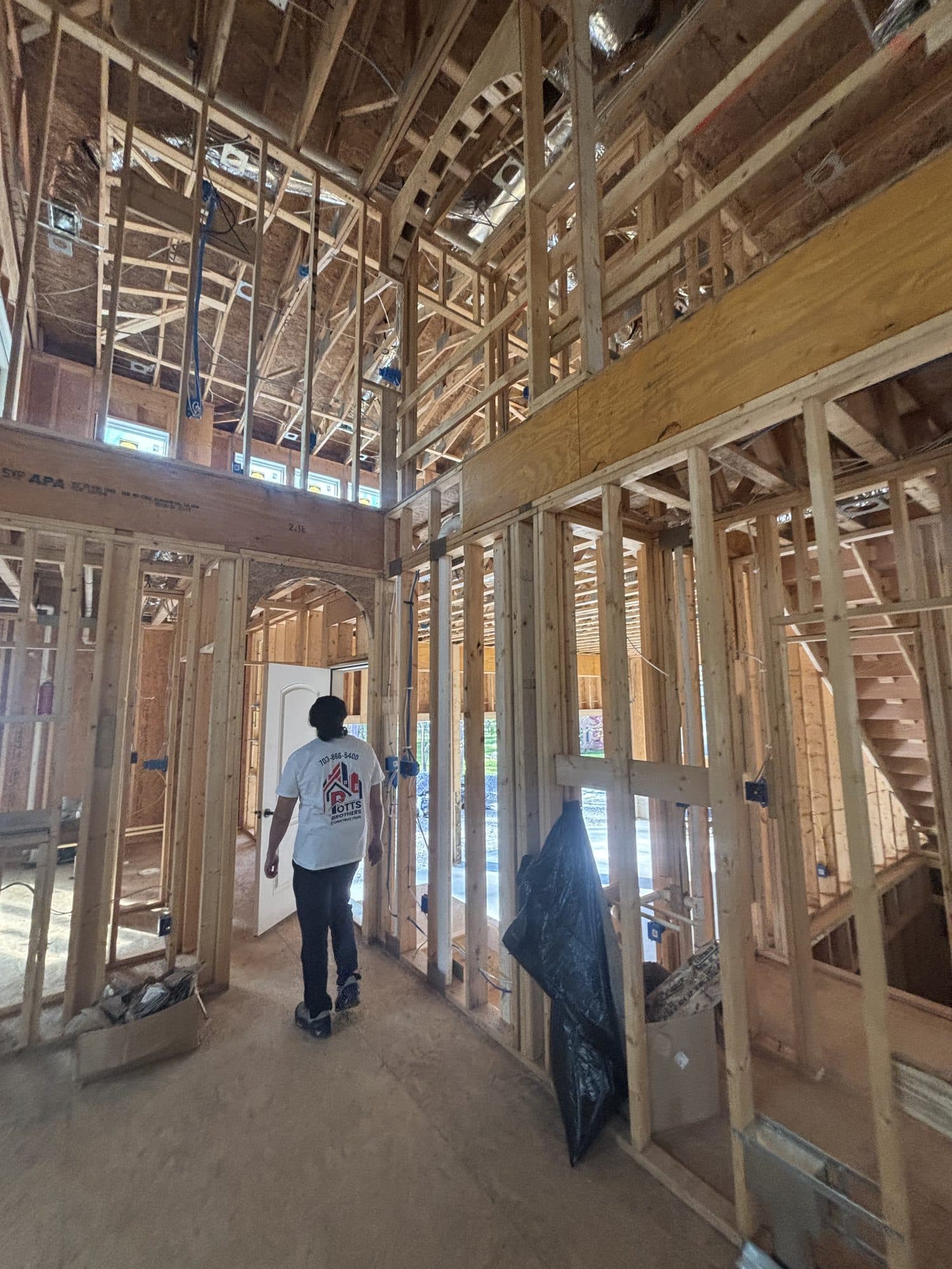 Worker in framed two story interior with stairca. Home addition project by Potts Brothers Construction, Arlington & Northern Virginia