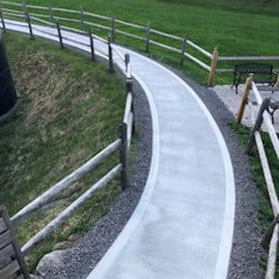 Curved concrete walkway with split-rail fence and bench. Concrete project by Potts Brothers Construction, Arlington & Northern Virginia