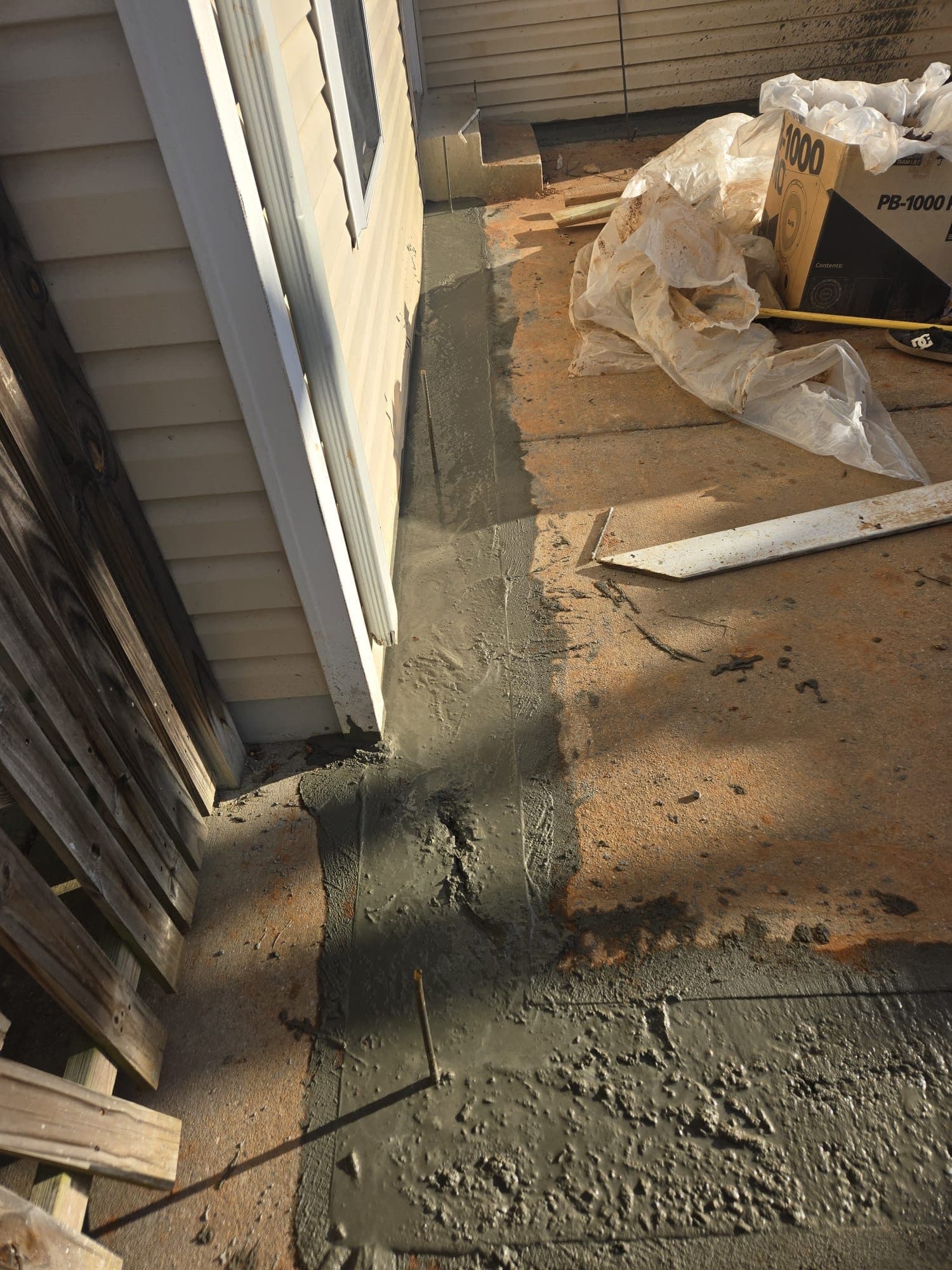 Freshly poured concrete patch along house edge. Concrete project by Potts Brothers Construction, Arlington & Northern Virginia