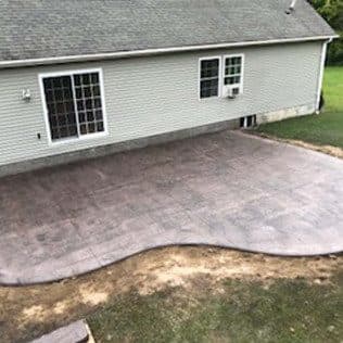 Stamped concrete patio behind green-sided home. Concrete project by Potts Brothers Construction, Arlington & Northern Virginia