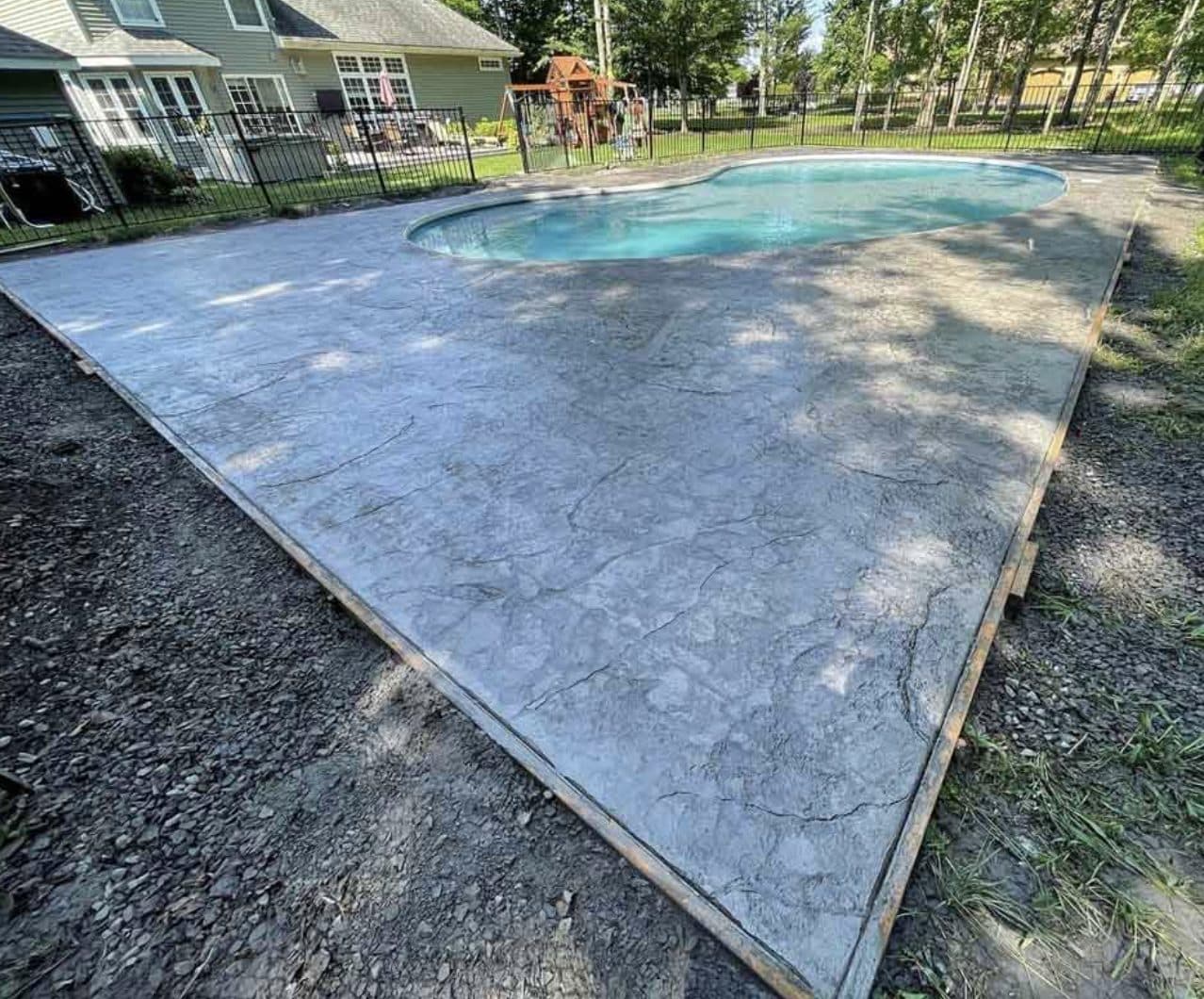 Stamped concrete pool deck surrounding backyard pool. Concrete project by Potts Brothers Construction, Arlington & Northern Virginia