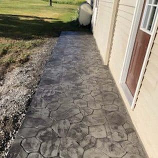 Stamped concrete walkway alongside tan-sided house. Concrete project by Potts Brothers Construction, Arlington & Northern Virginia