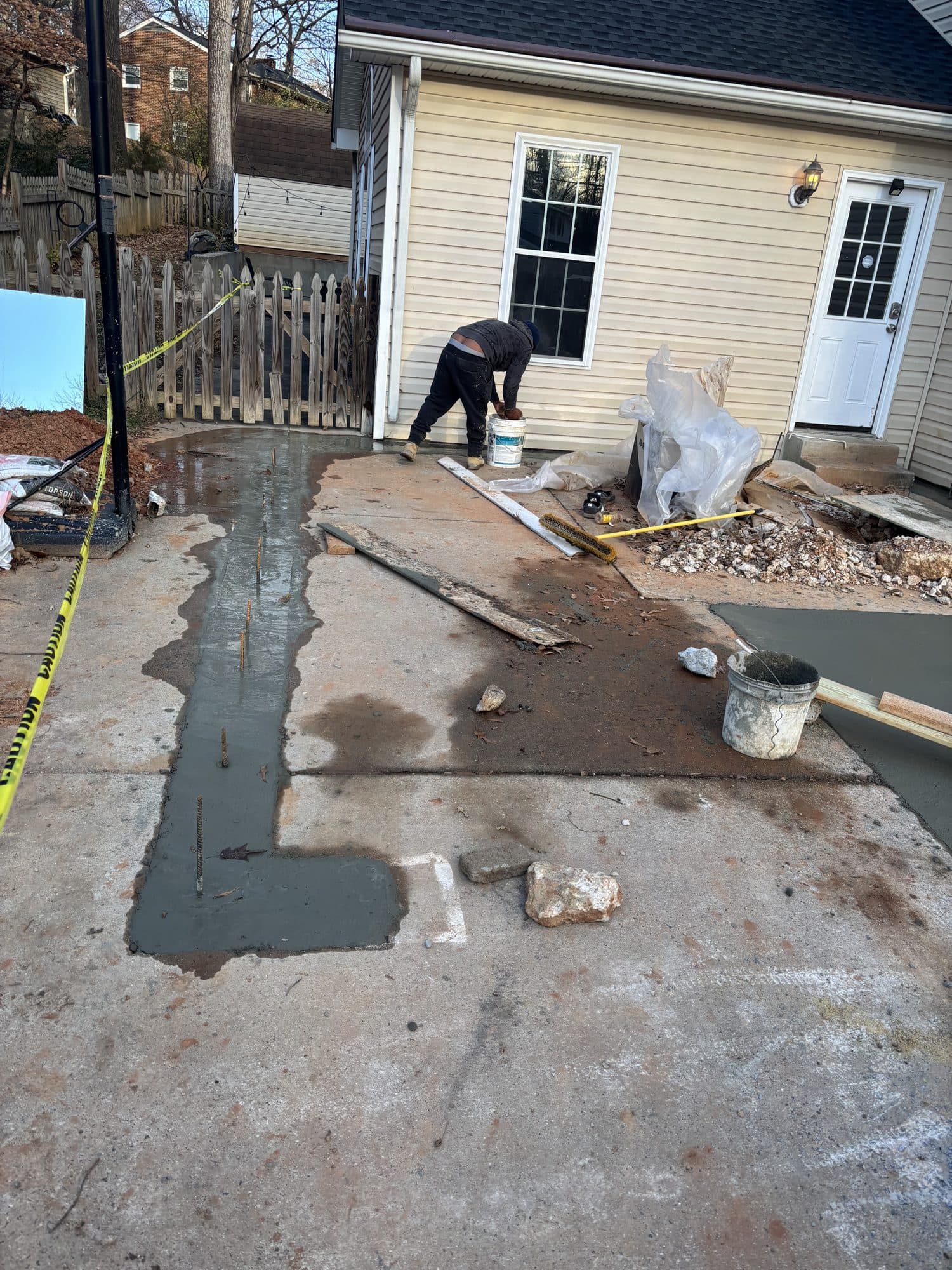 Worker finishing fresh concrete patio behind hou. Concrete project by Potts Brothers Construction, Arlington & Northern Virginia