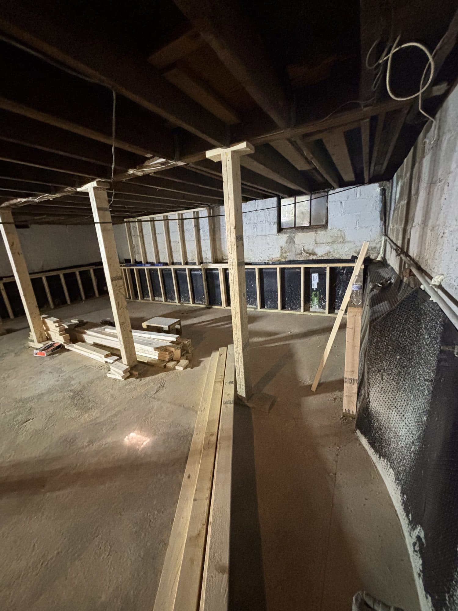 Basement underpinning with support posts and drainage board. Foundation project by Potts Brothers Construction, Arlington & Northern Virginia