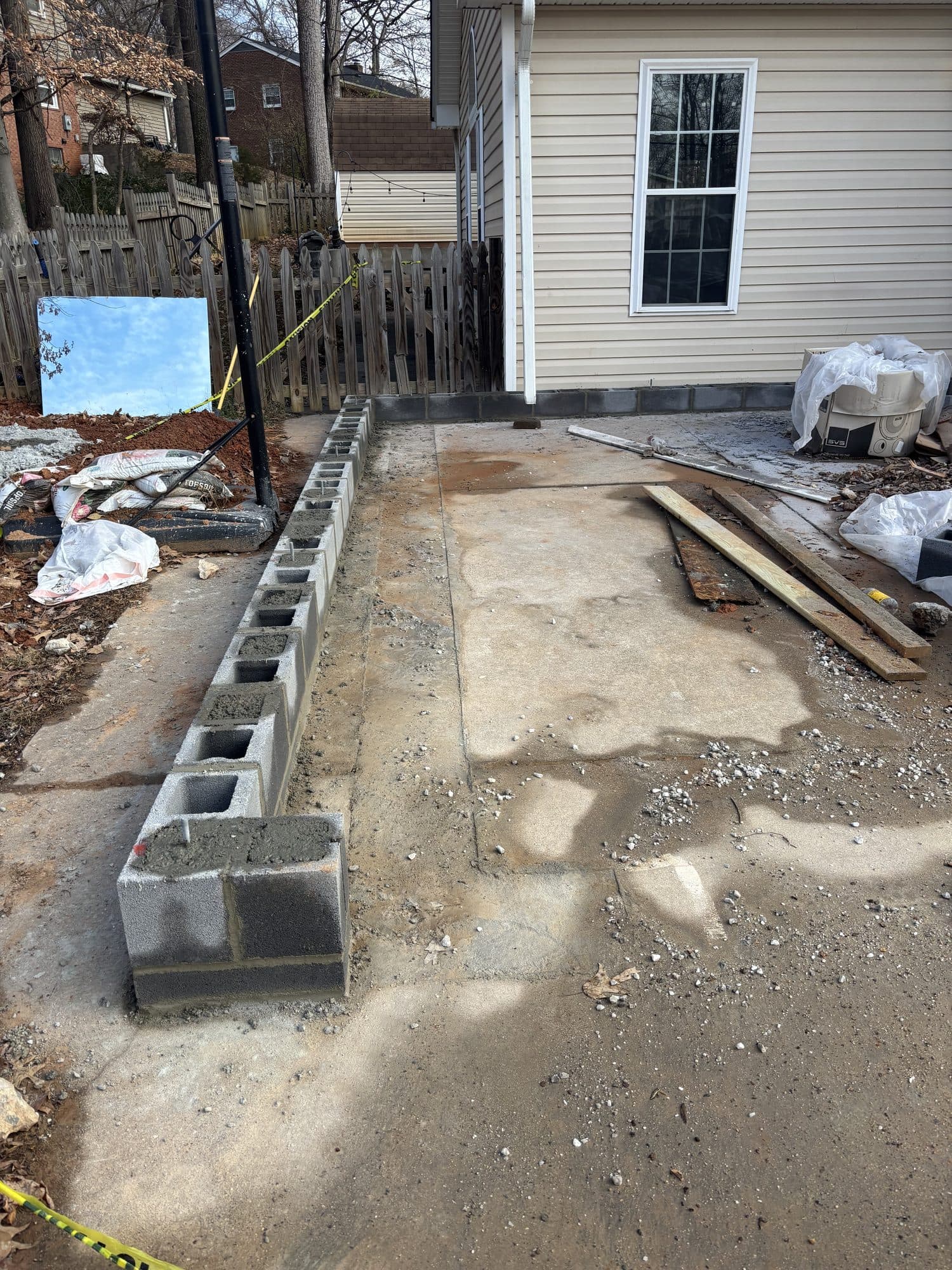 A course of concrete block forming a low wall along a concrete patio slab next to a house. Foundation project by Potts Brothers Construction, Arlington & Northern Virginia