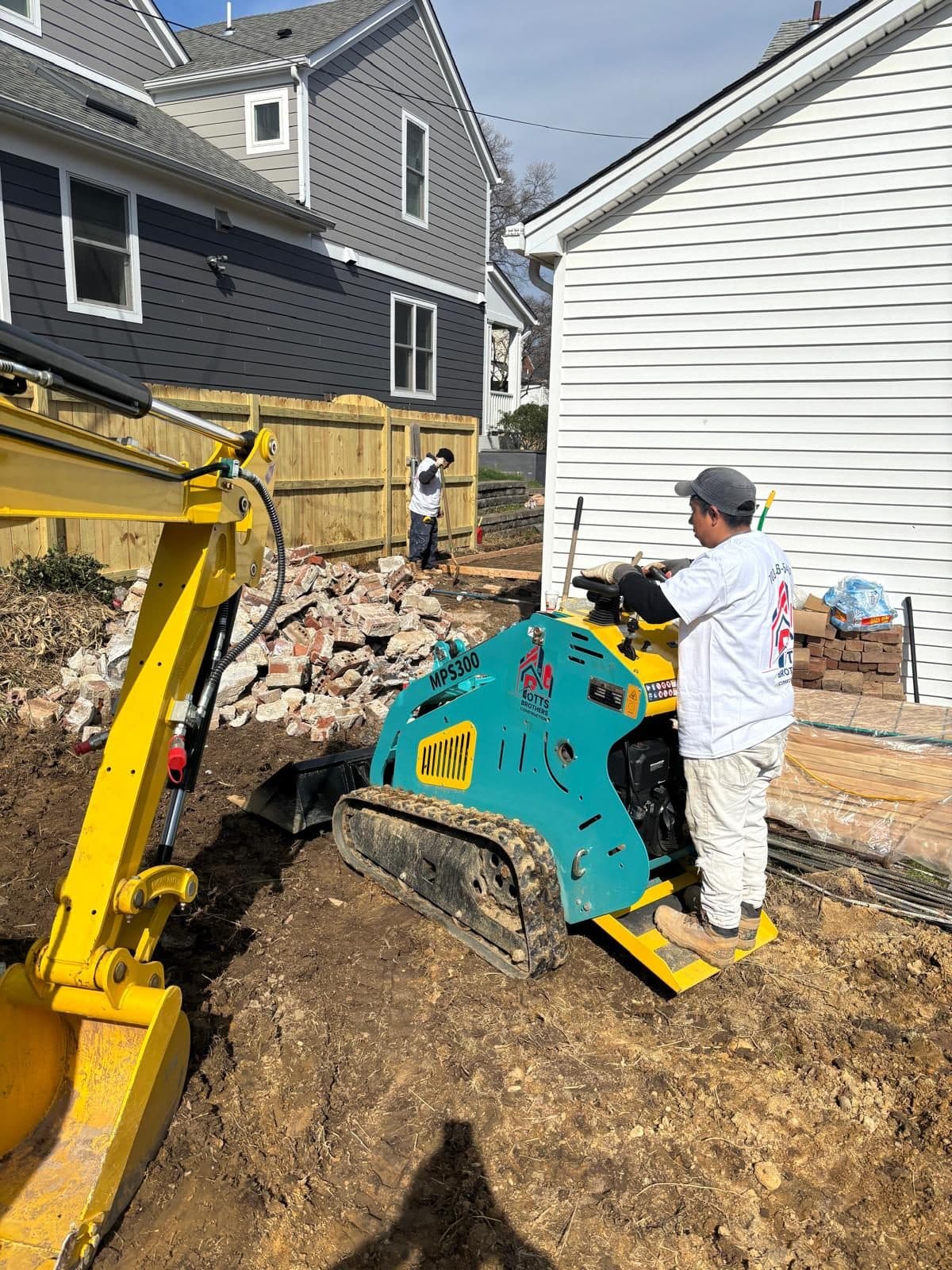 Crew operating track loader backyard. Foundation project by Potts Brothers Construction, Arlington & Northern Virginia