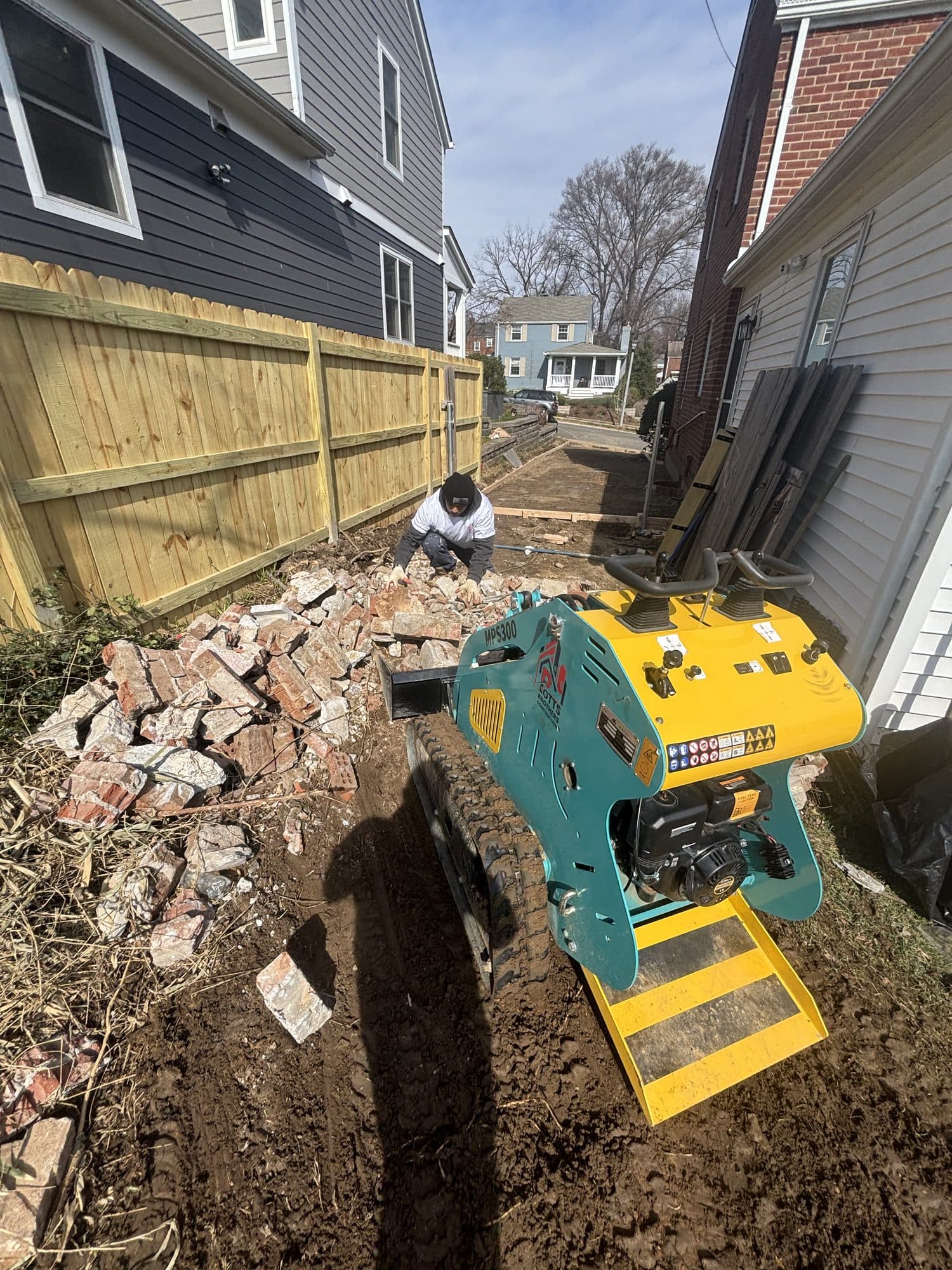 Excavation alongside home with mini track loader. Foundation project by Potts Brothers Construction, Arlington & Northern Virginia