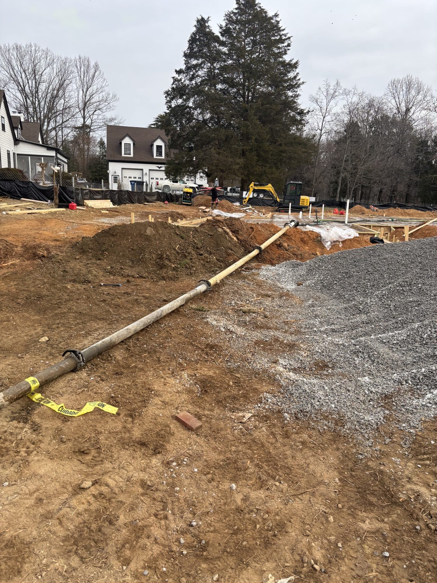Graded foundation site with gravel and excavator. Foundation project by Potts Brothers Construction, Arlington & Northern Virginia