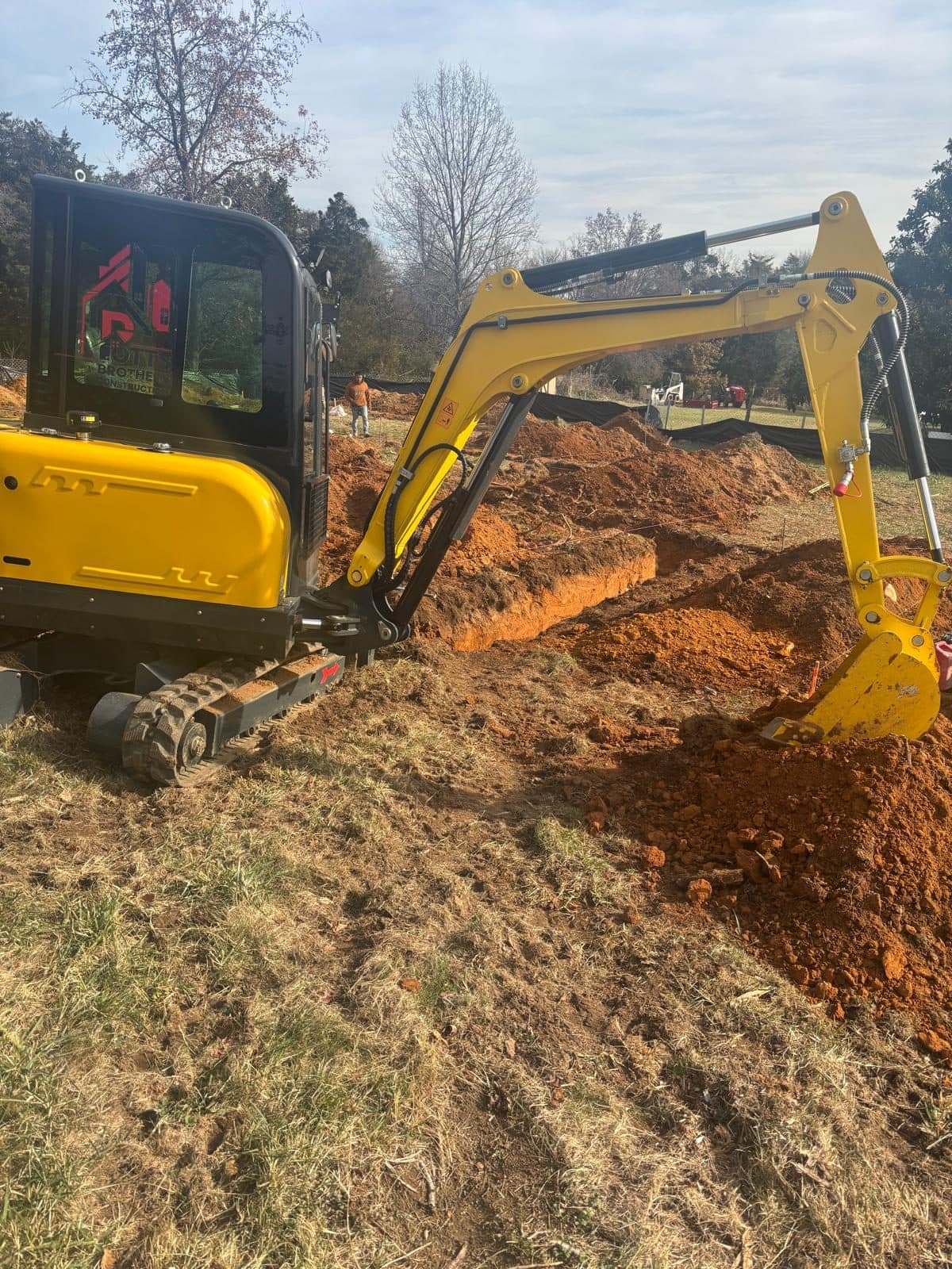 Mini excavator digging footing trench. Foundation project by Potts Brothers Construction, Arlington & Northern Virginia