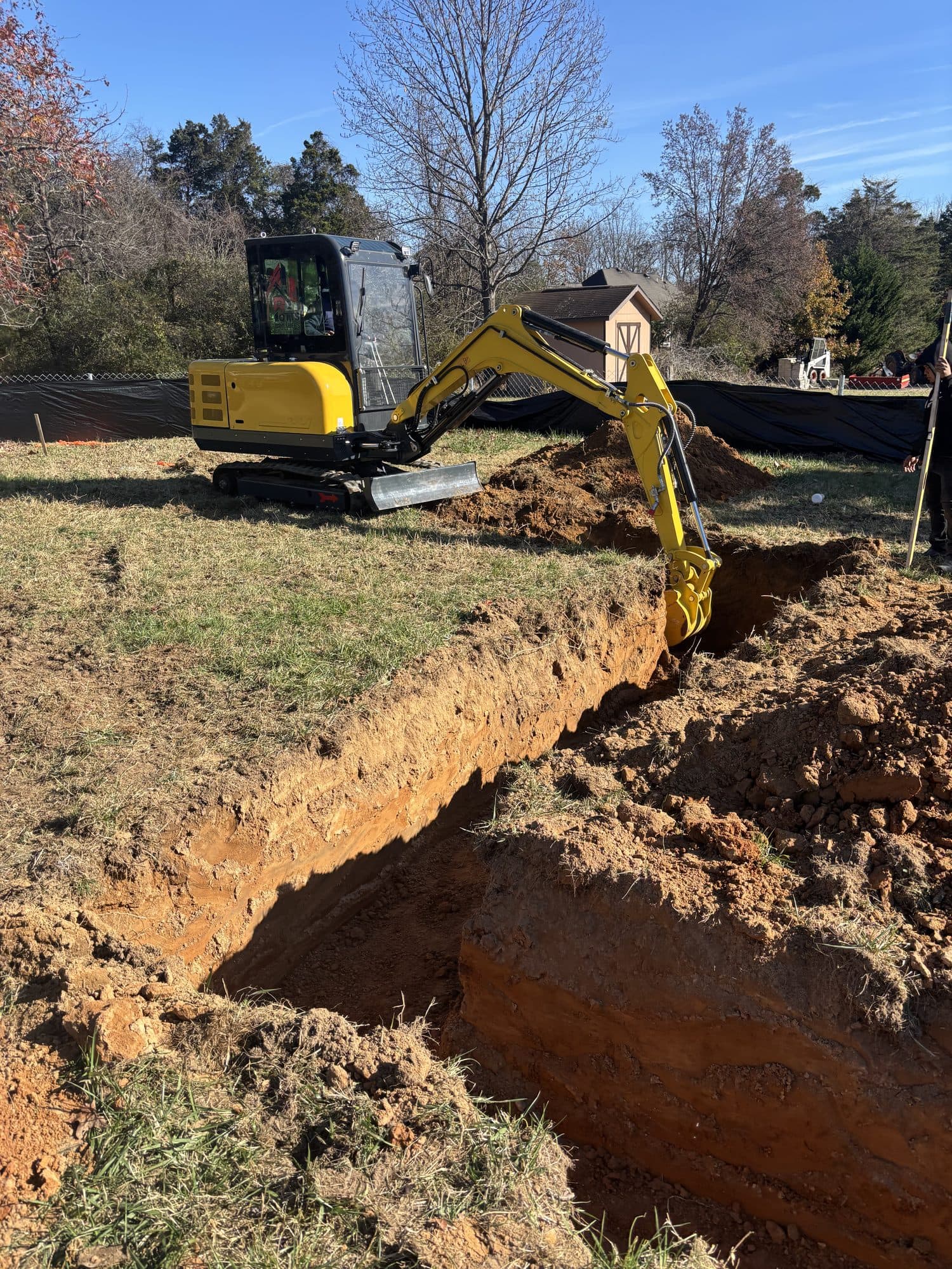 Mini excavator digging foundation footing. Foundation project by Potts Brothers Construction, Arlington & Northern Virginia