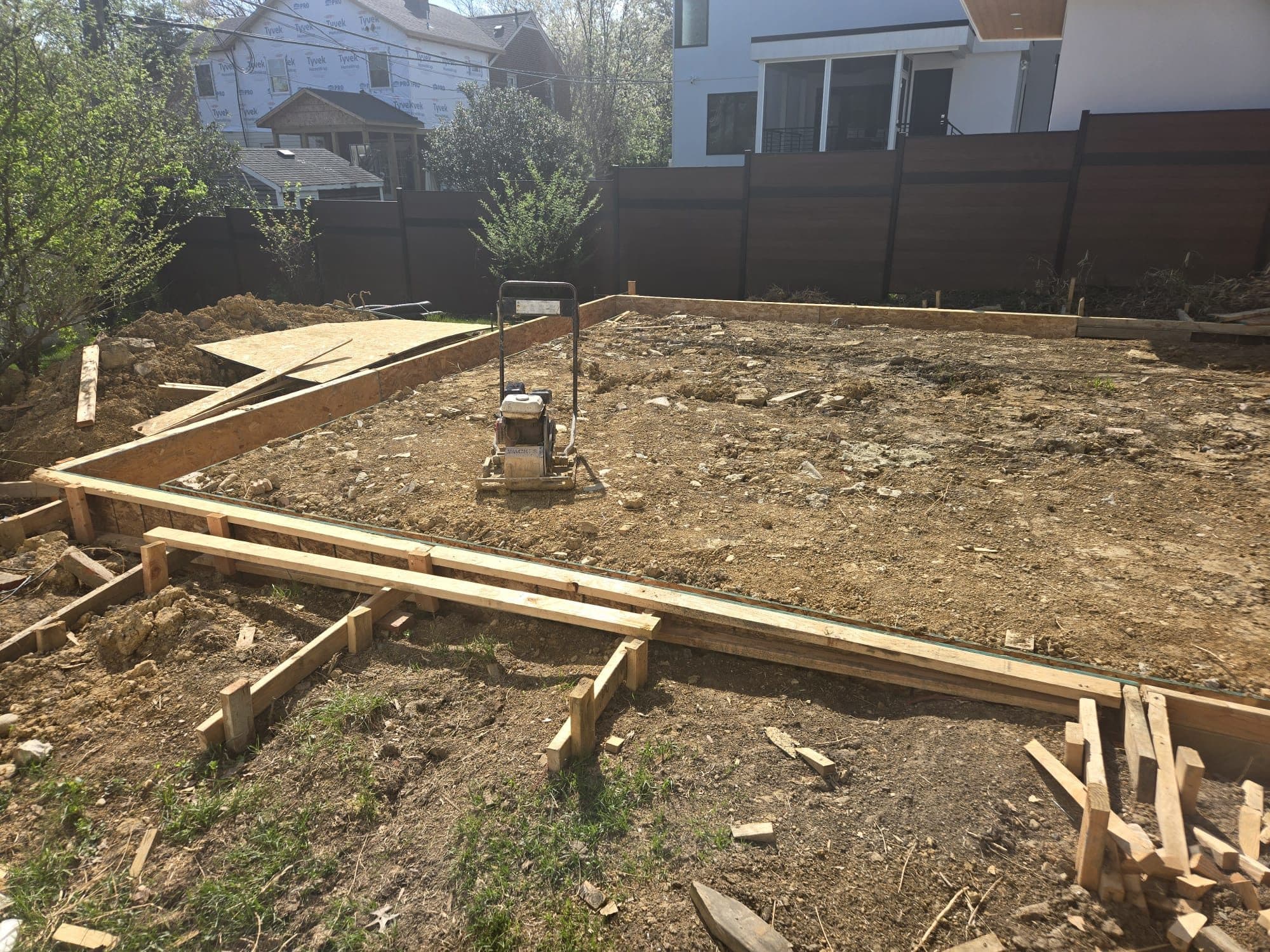 Plate compactor on graded soil within foundation forms. Foundation project by Potts Brothers Construction, Arlington & Northern Virginia