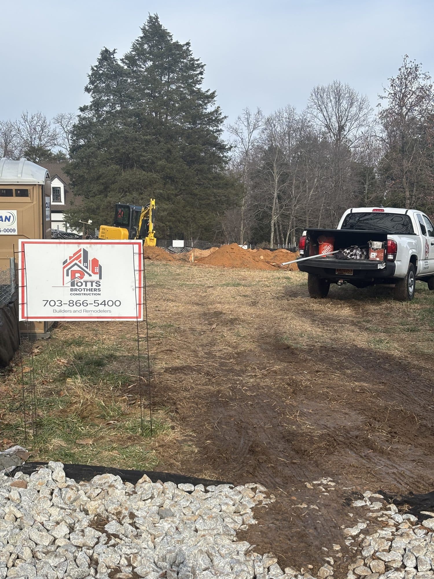Site prep with excavator and dirt mounds. Foundation project by Potts Brothers Construction, Arlington & Northern Virginia