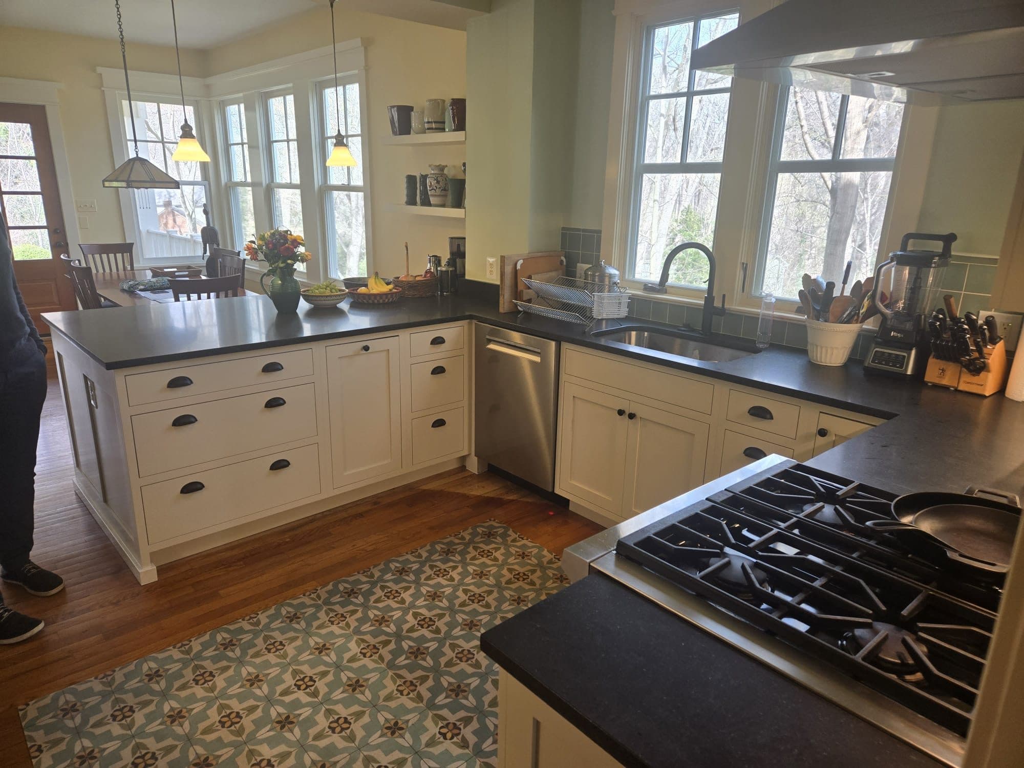 A bright remodeled kitchen with white cabinetry, dark countertops, a gas-cooktop island, and a patterned tile rug. Home addition project by Potts Brothers Construction, Arlington & Northern Virginia