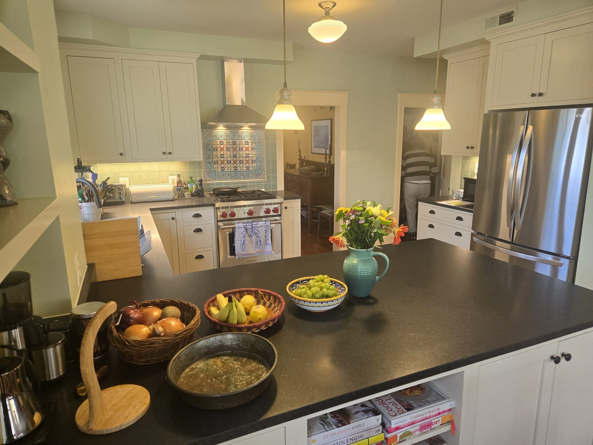 A remodeled white kitchen with a dark stone island, stainless range and refrigerator, and decorative tile backsplash. Home addition project by Potts Brothers Construction, Arlington & Northern Virginia